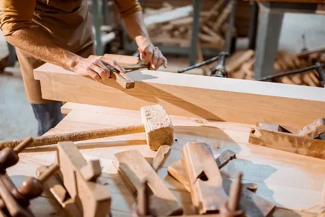 Un hombre está trabajando en un trozo de madera en un taller.