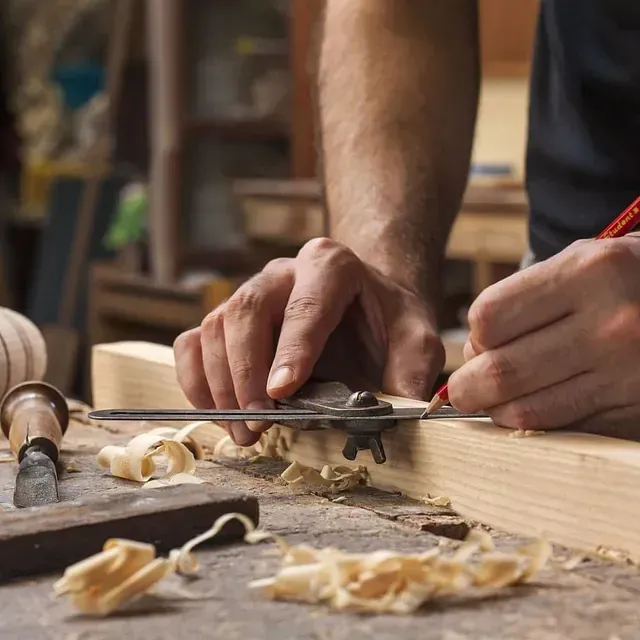Un hombre está midiendo un trozo de madera con una regla.