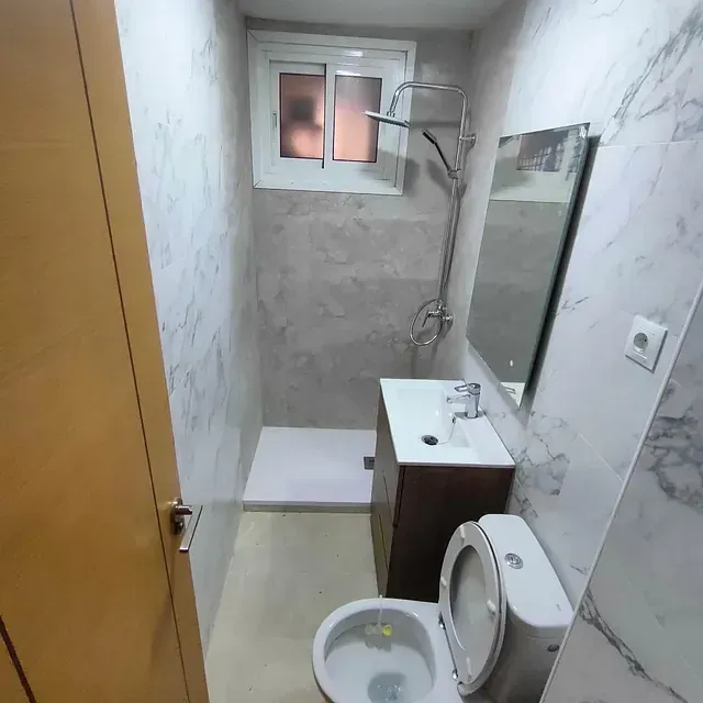 Un baño con inodoro, lavabo, ducha y espejo.