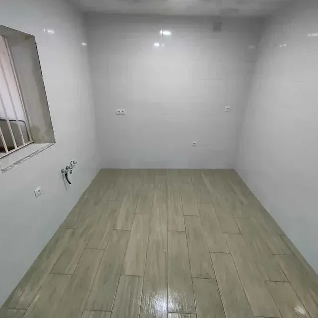 Una habitación con suelo de madera y paredes blancas.