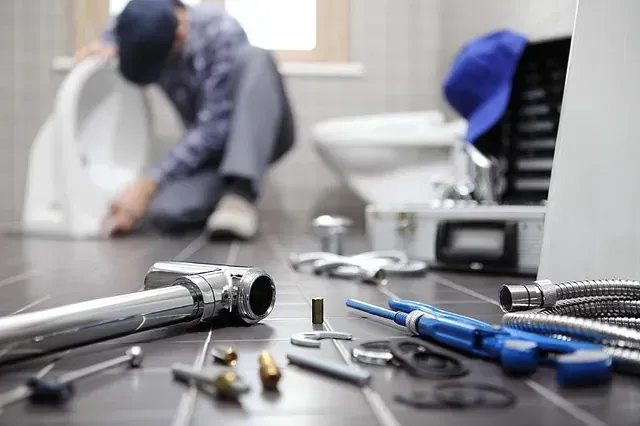 Un fontanero está trabajando en un inodoro en un baño.
