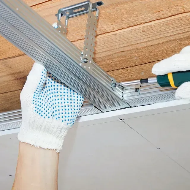 Una persona con guantes está trabajando en un techo con un destornillador.