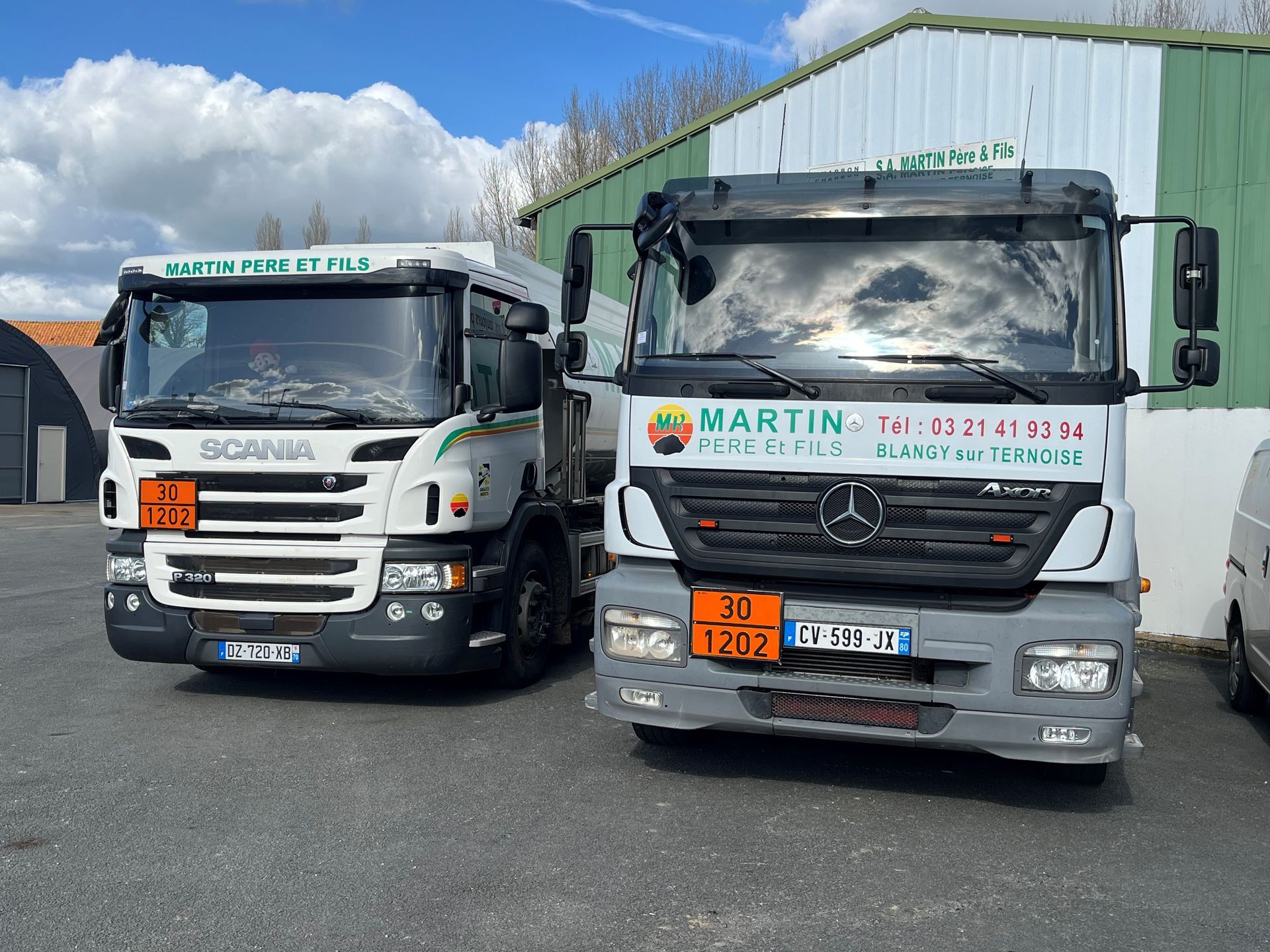 Deux camions-citernes commerciaux stationnés côte à côte sur un parking, portant des panneaux de danger et l'inscription Martin Père Et Fils.