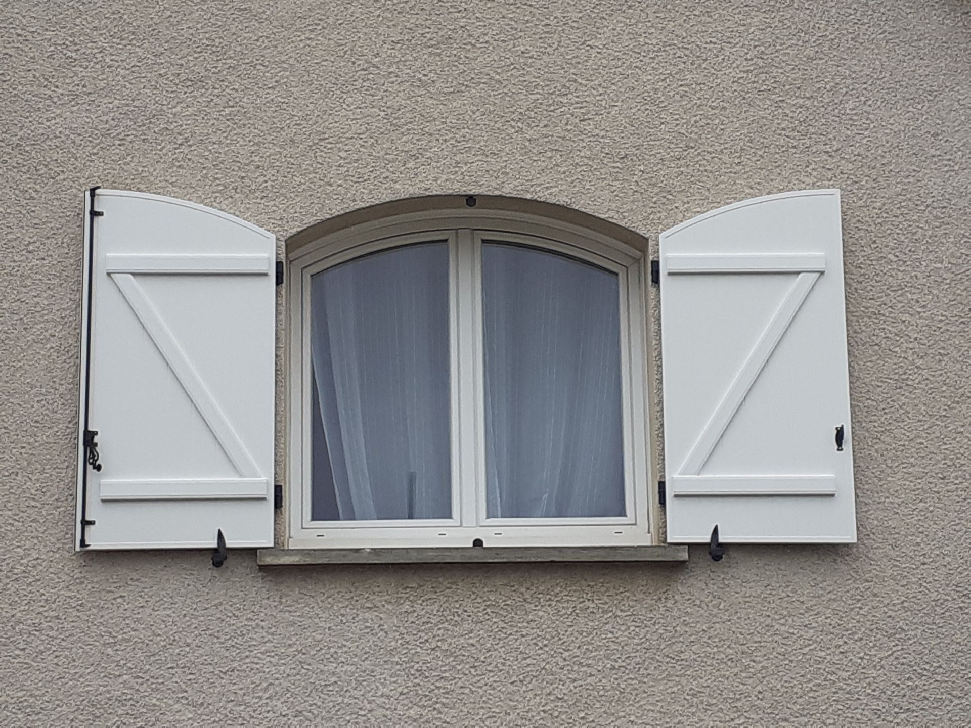 Fenêtre arrondie avec volets blancs