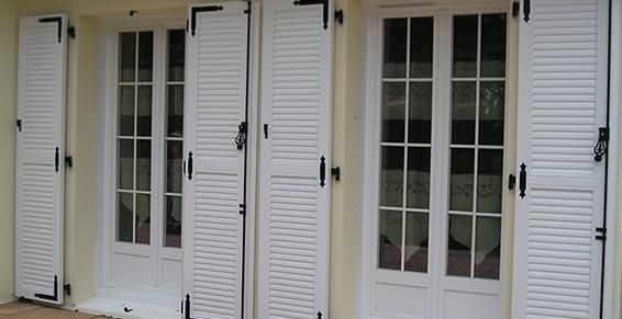 Deux portes-fenêtres blanches avec croisillons et volets blancs