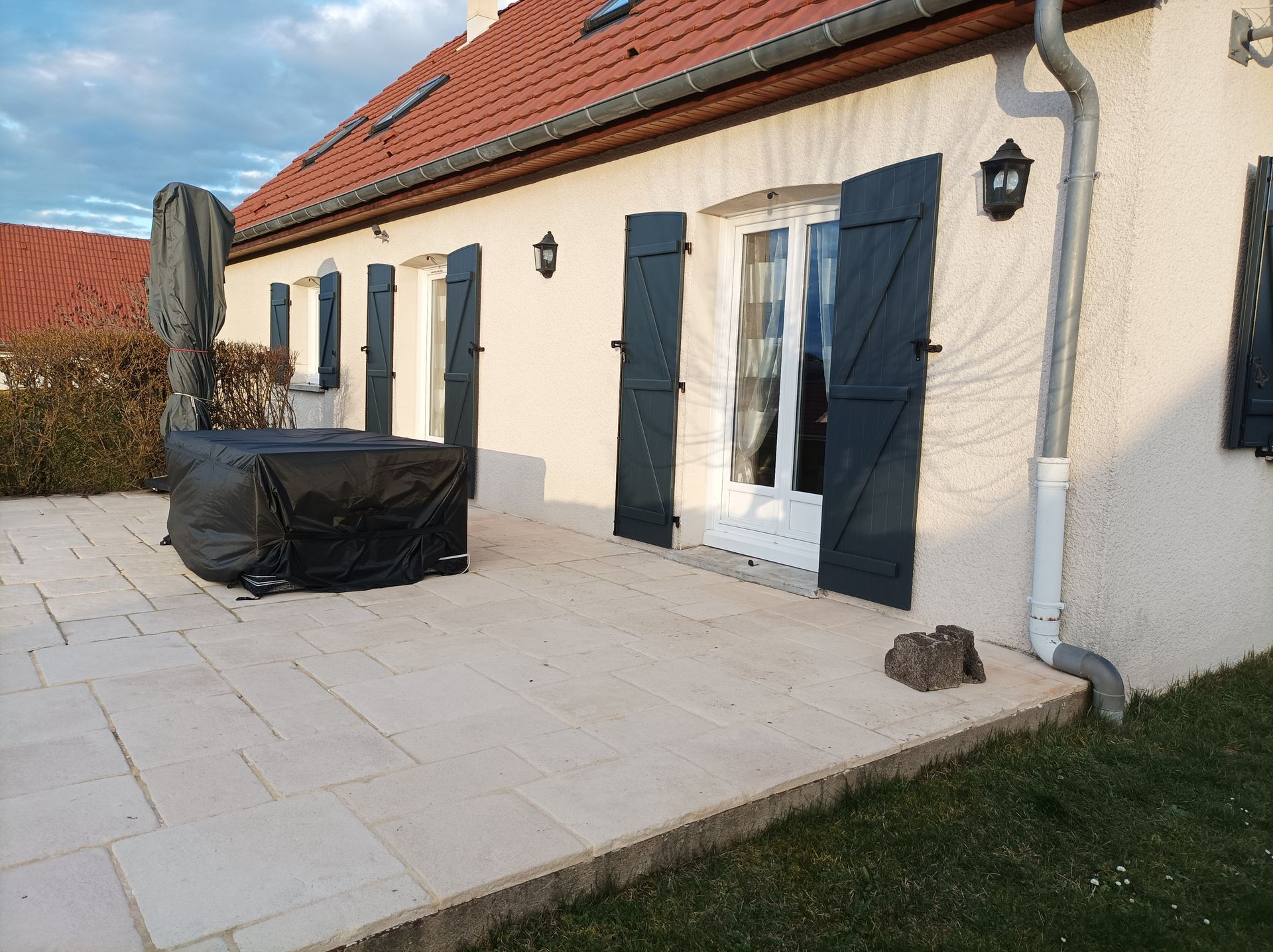 Terrasse de maison avec portes-fenêtres blanches et volets gris anthracite