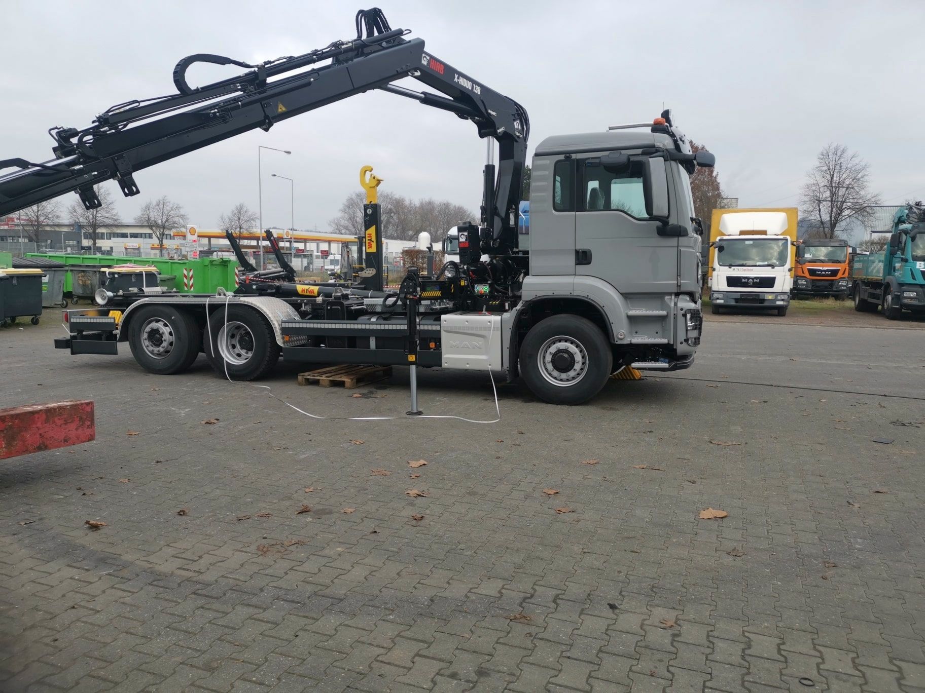 Auf einem Parkplatz steht ein LKW mit einem daran befestigten Kran.