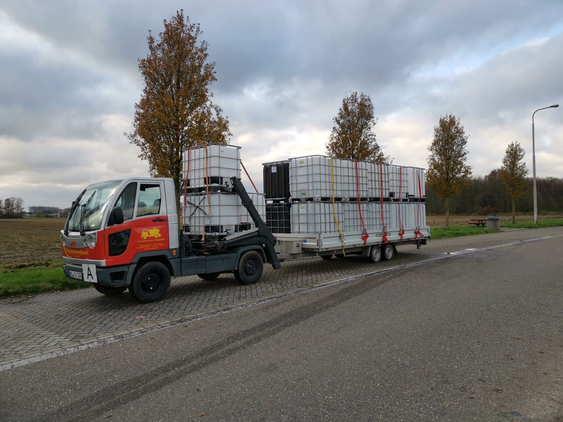 Ein LKW zieht einen Anhänger voller Container eine Straße entlang.