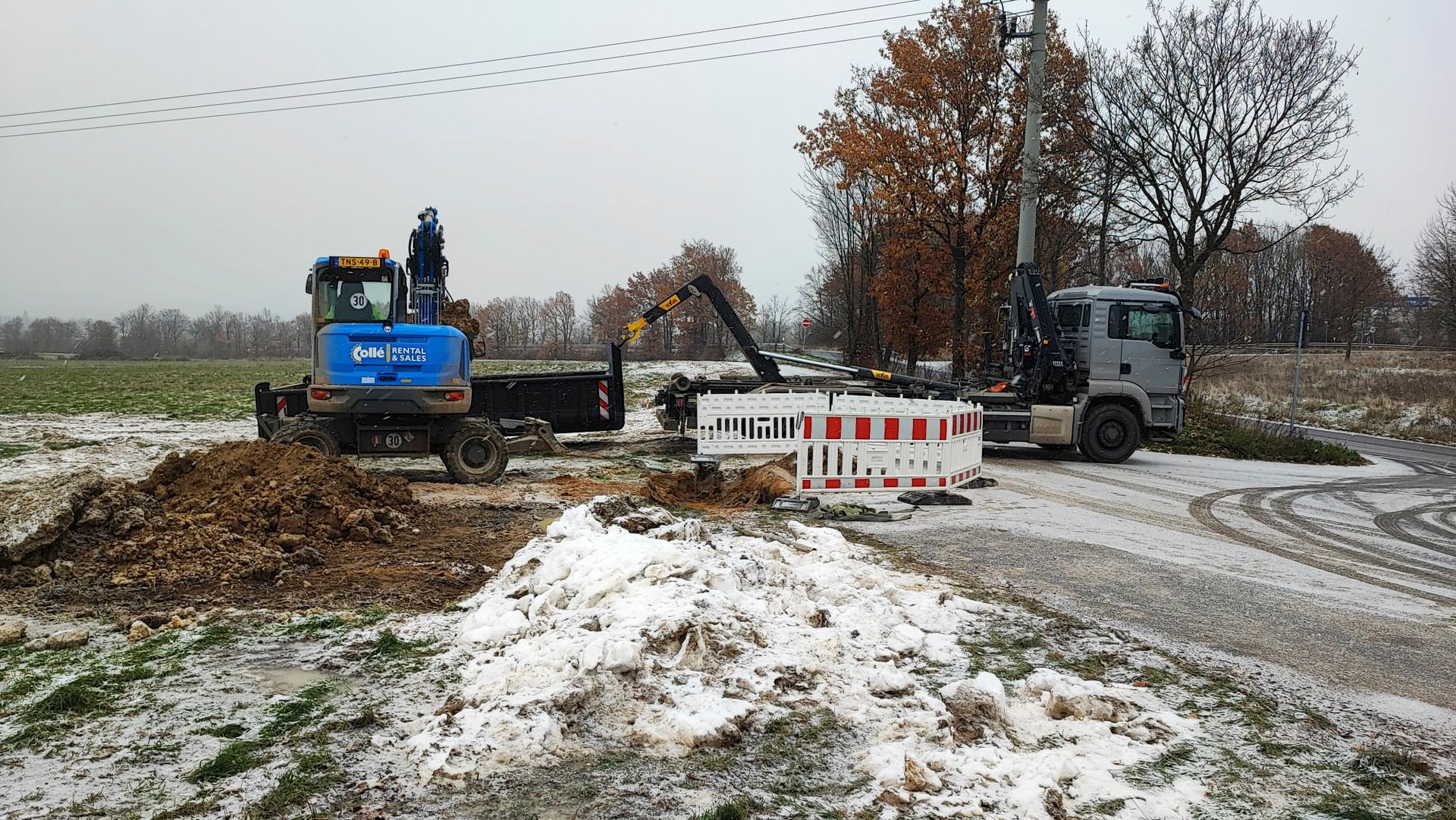 Ein Baufahrzeug fährt auf einer verschneiten Straße neben einem Lastwagen her.