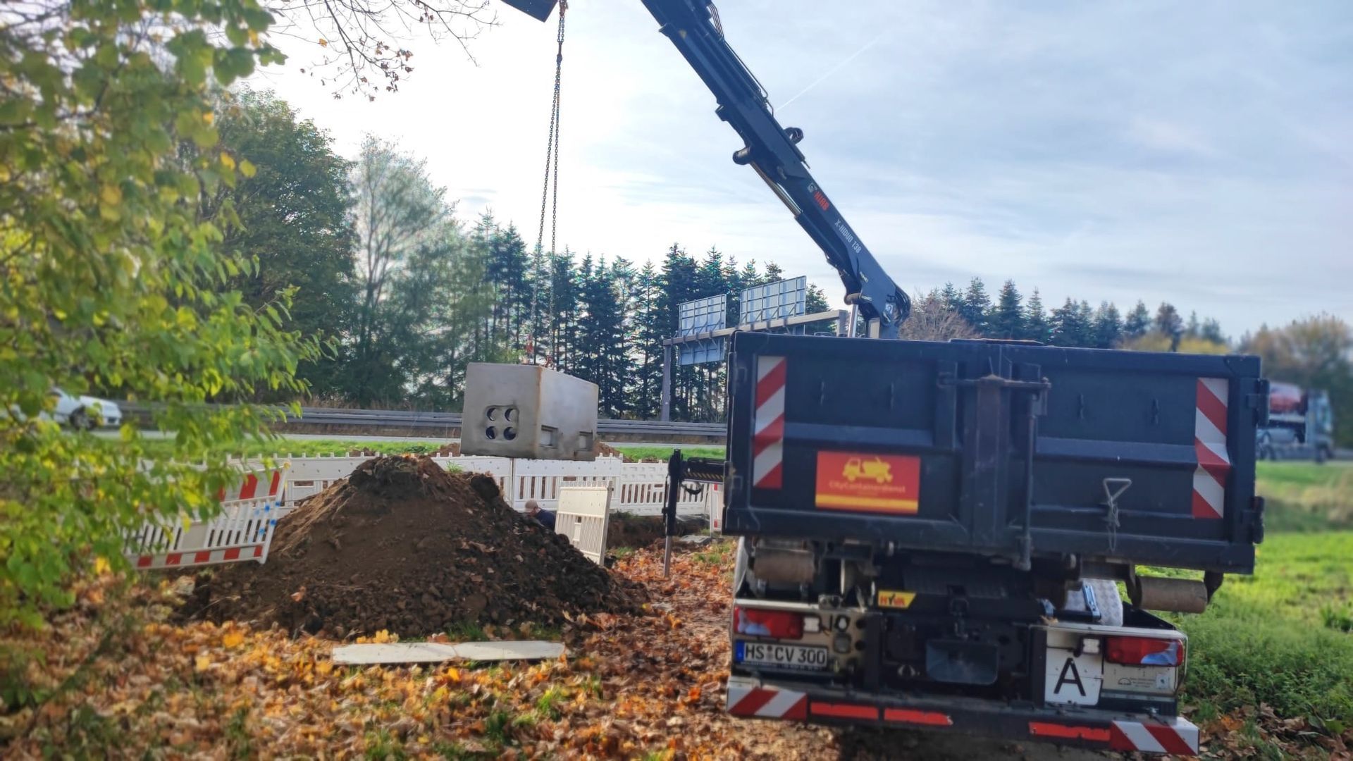 Ein Muldenkipper mit einem daran befestigten Kran transportiert einen Haufen Erde.