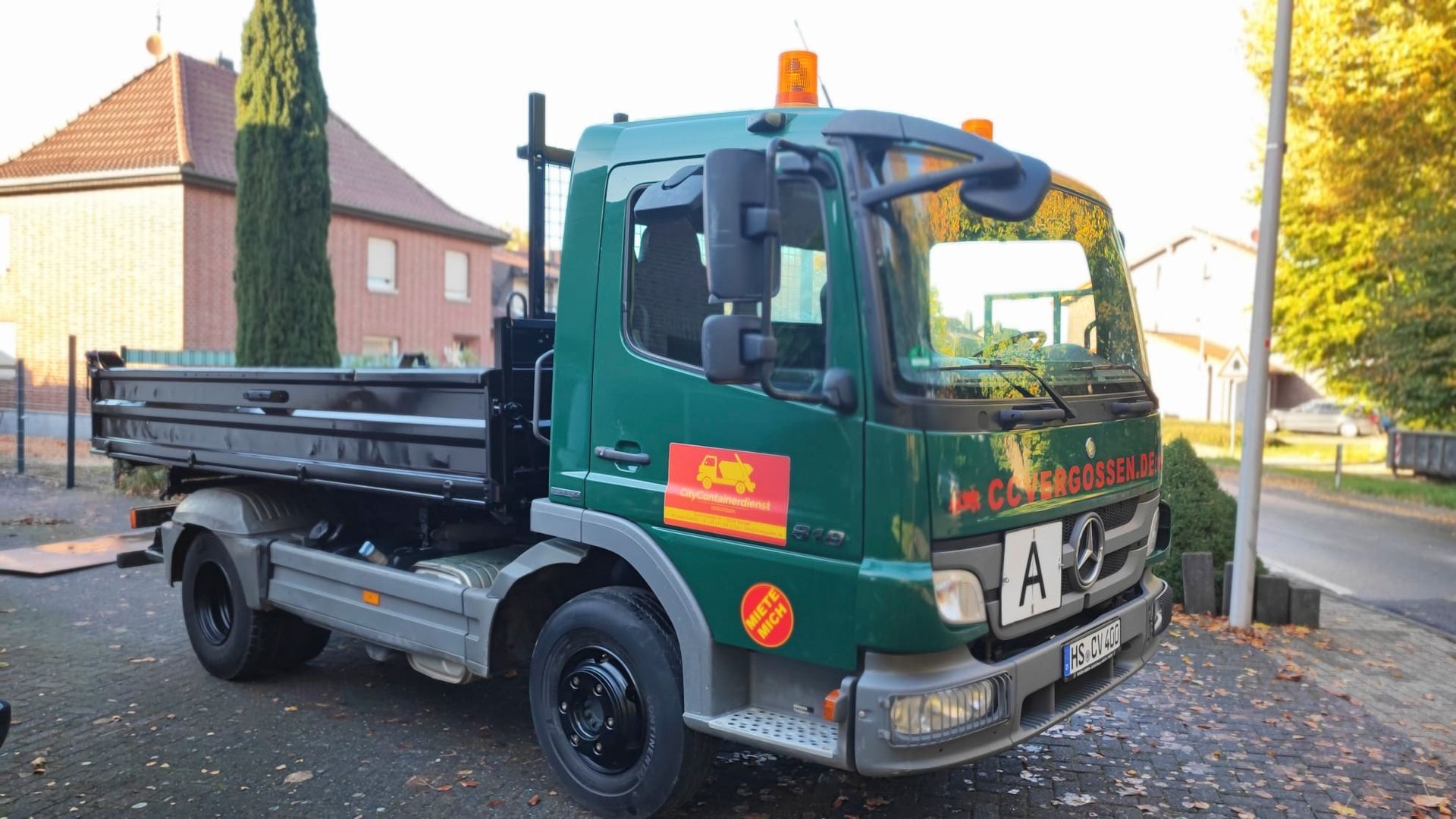 Ein grüner Muldenkipper steht am Straßenrand
