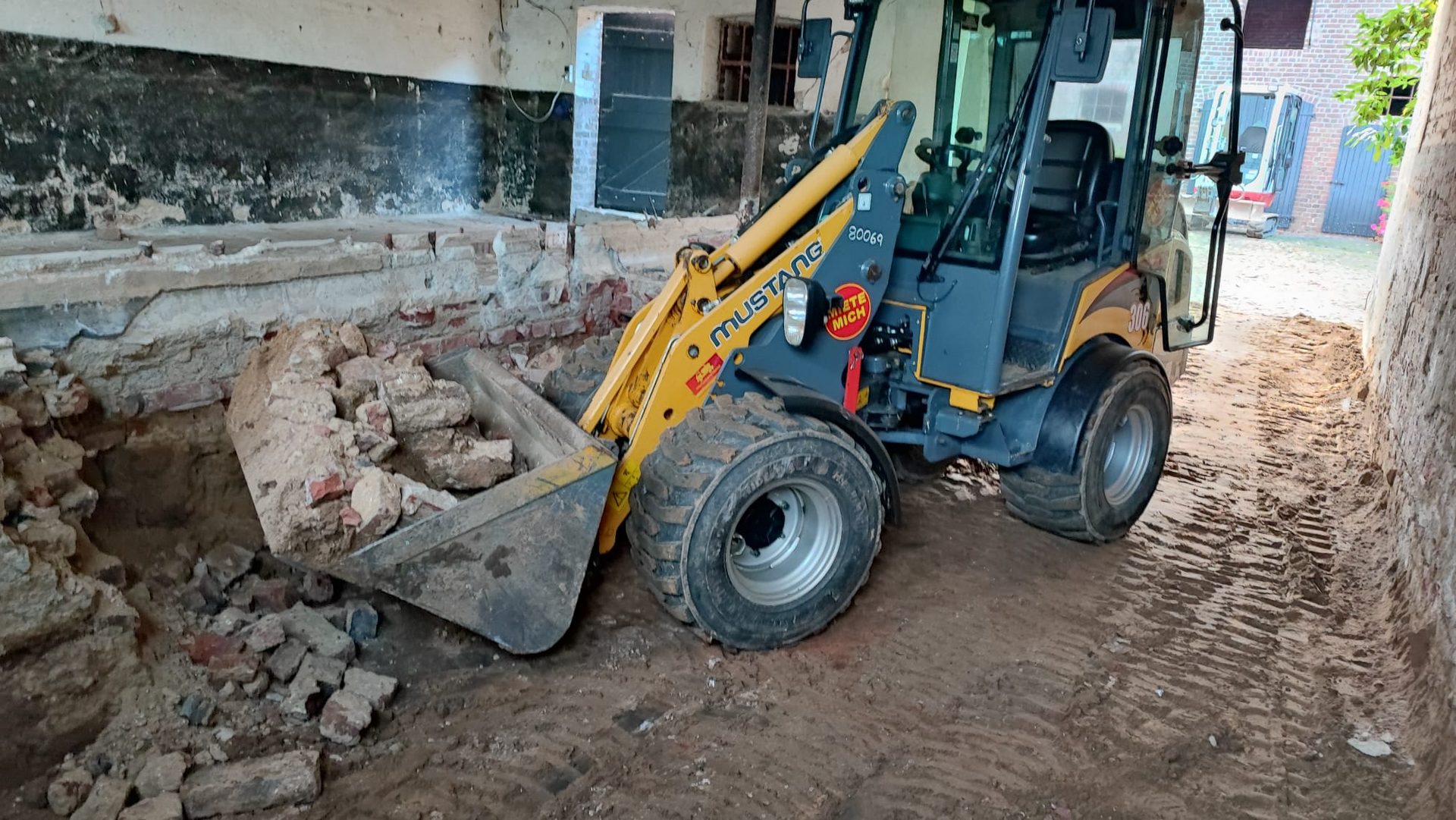 Ein kleiner Bulldozer bewegt Erde und Steine in einem Gebäude.