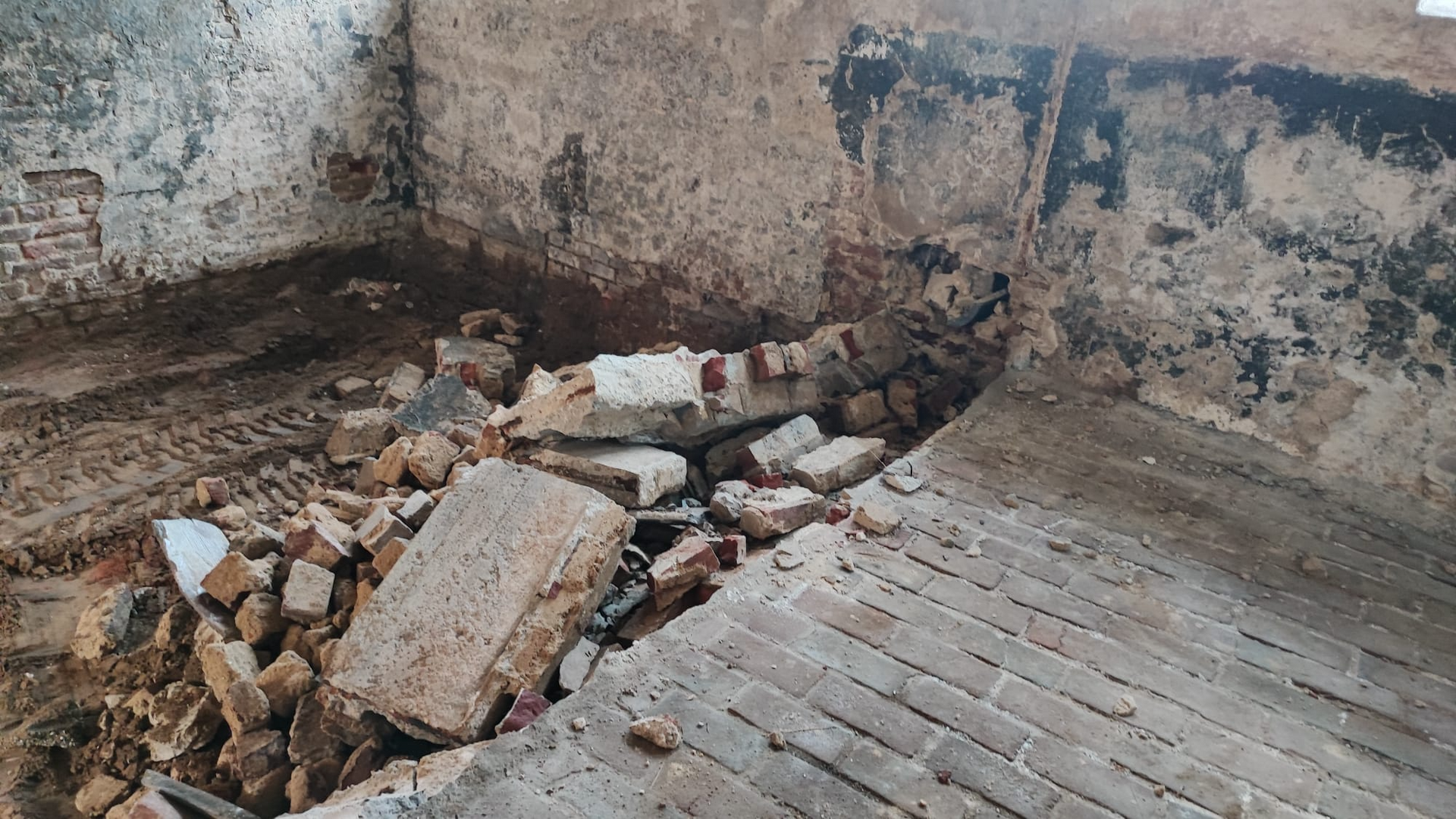 Ein Stapel Ziegelsteine liegt neben einer Mauer auf dem Boden.