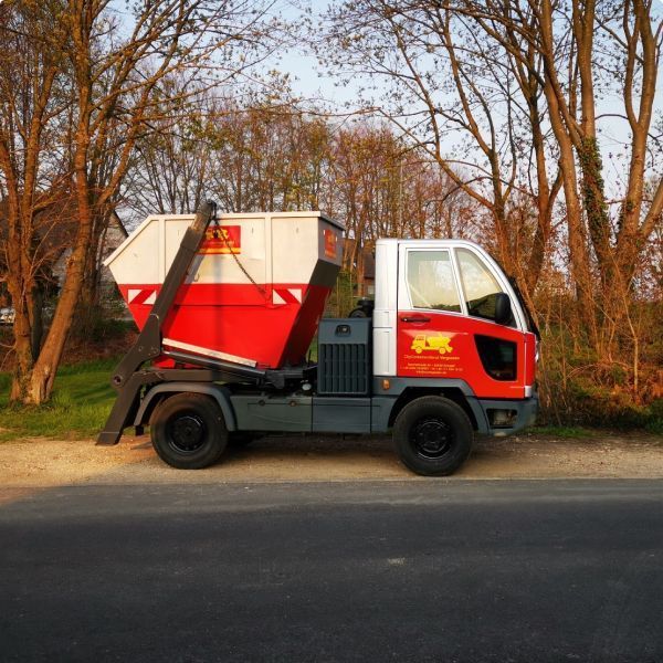 Ein rot-weißer Muldenkipper steht am Straßenrand