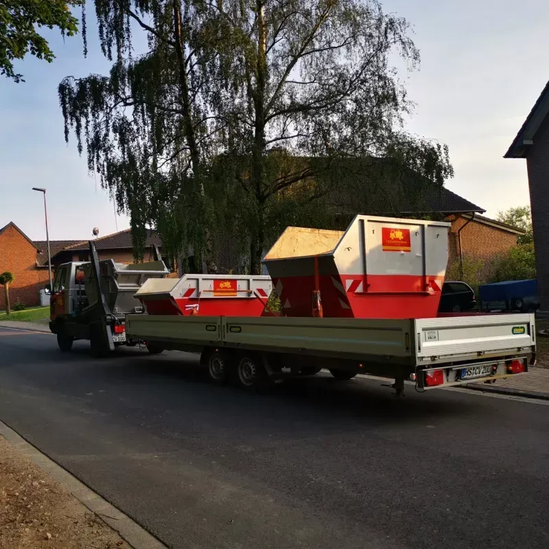 Ein rot-weißer Müllcontainer steht auf der Ladefläche eines LKWs