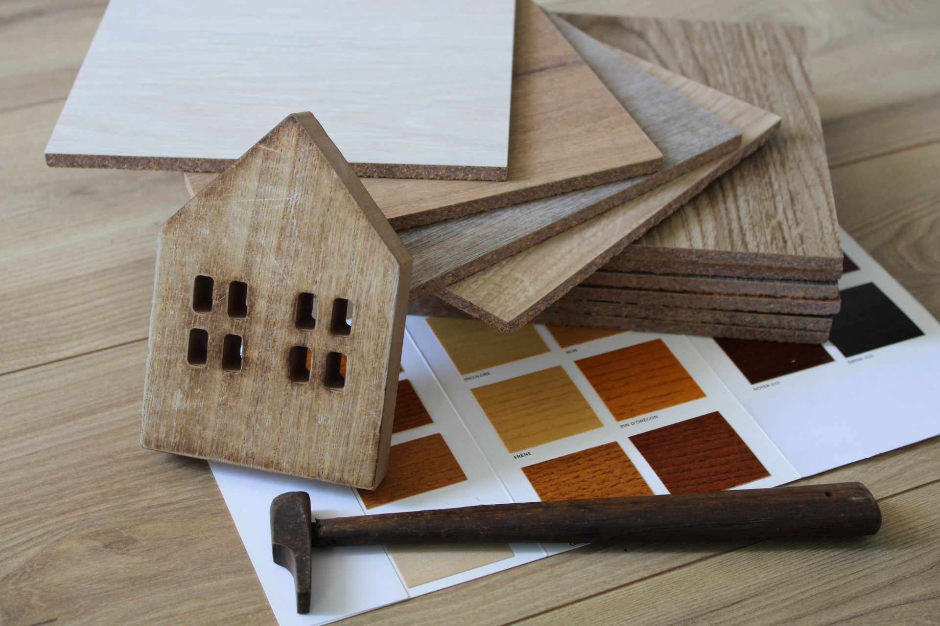 Maison en bois miniature marteau et échantillons de parquets aux nuances variées