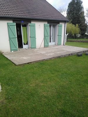 Travaux de terrasse, vue façade de maison aux volets verts