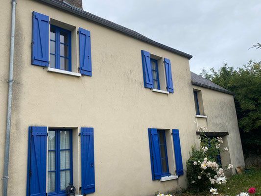 Façade de maison avec fenêtres et volets bleus