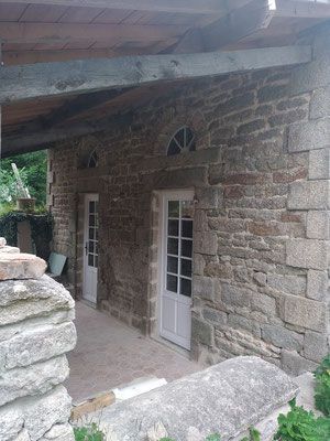 Vue sur la porte fenêtre blanche, façade de maison en pierre