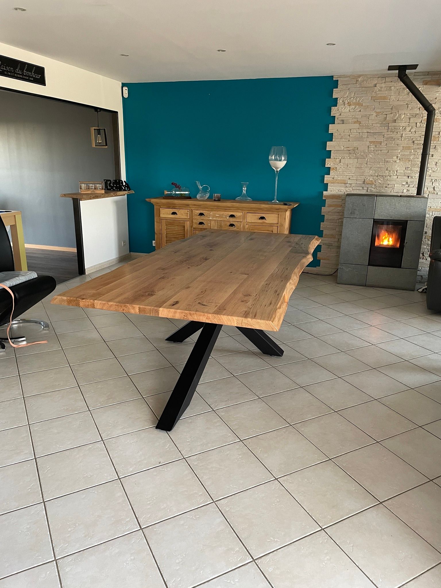 Table en bois clair sur pieds en bois foncé, vue sur un salon meublé