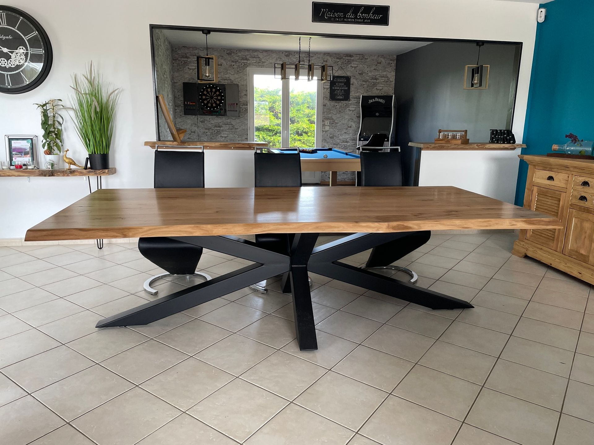 Table en bois clair sur pieds en bois foncé, vue sur la cuisine