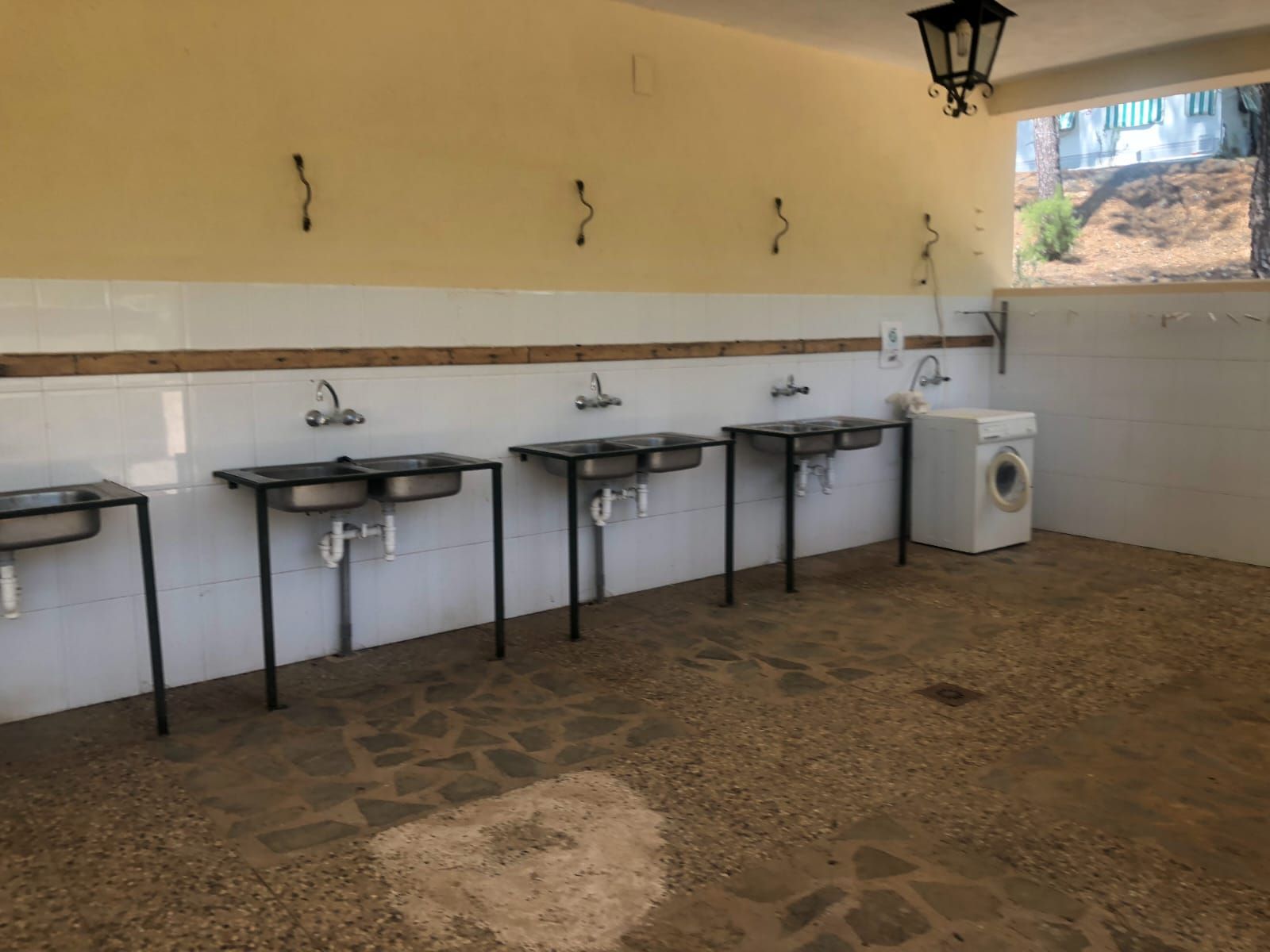 Estación de lavado exterior con varios lavabos y lavadora.
