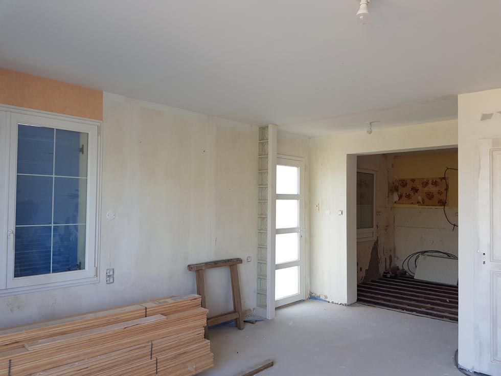 Intérieur d'une pièce en construction, avec une fenêtre, une porte et une entrée.