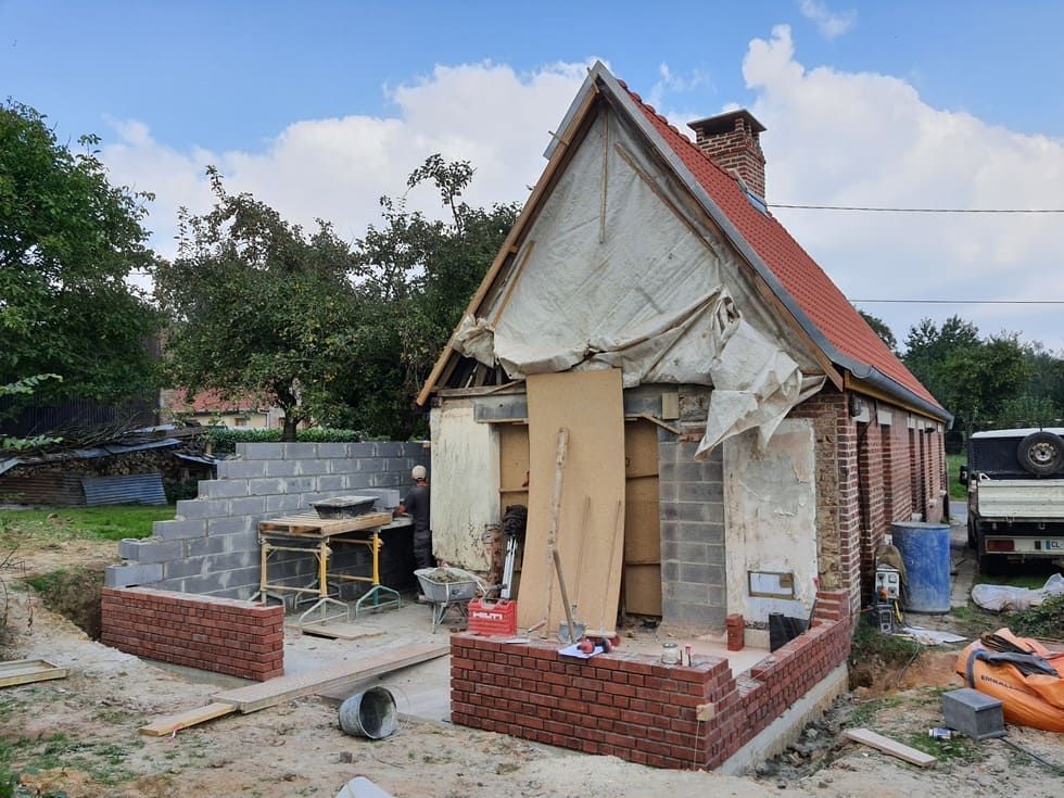 Construction d'une maison en briques avec intérieur apparent et mur en briques partiellement achevé.