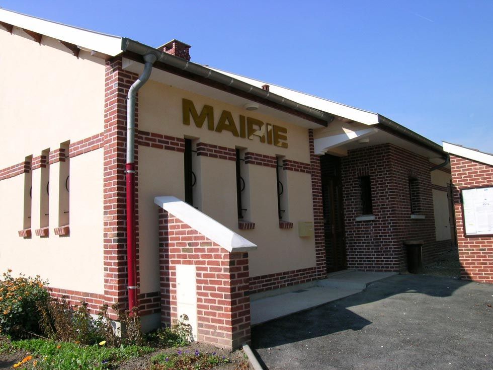Bâtiment de la mairie avec des murs beiges, des accents de briques rouges et une enseigne.