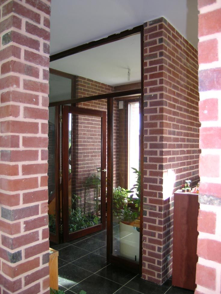 Porte en briques avec portes vitrées et sol carrelé foncé.