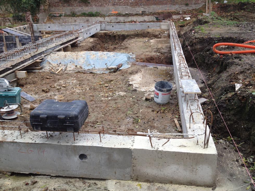 Fondations en béton en construction, avec armatures apparentes et terrain excavé.