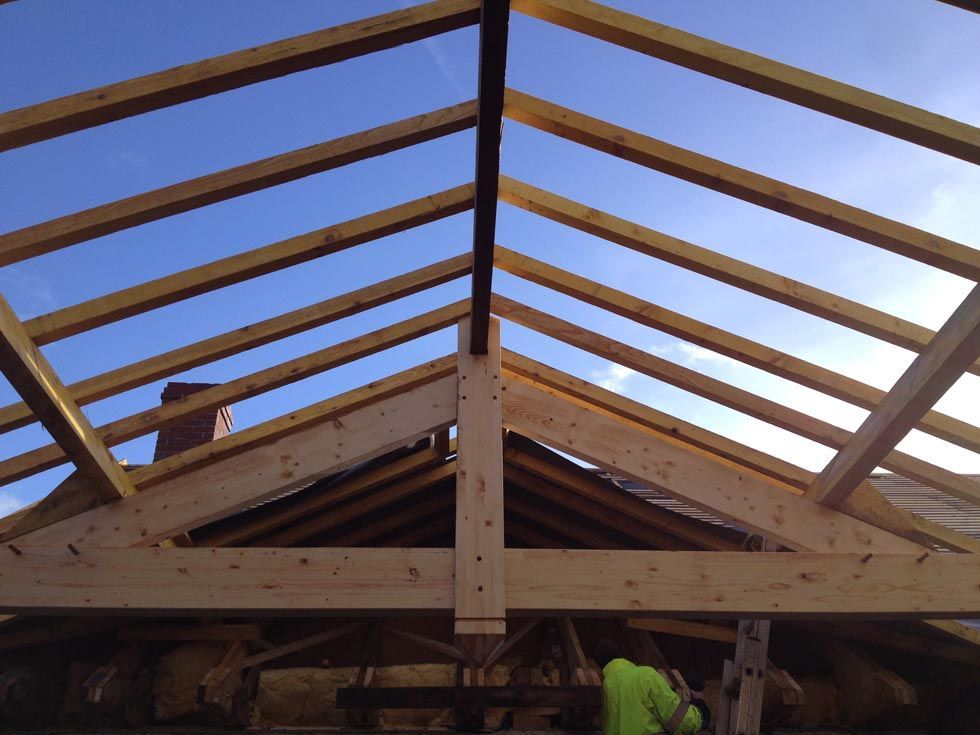 Charpente en bois en construction, se détachant sur un ciel bleu.