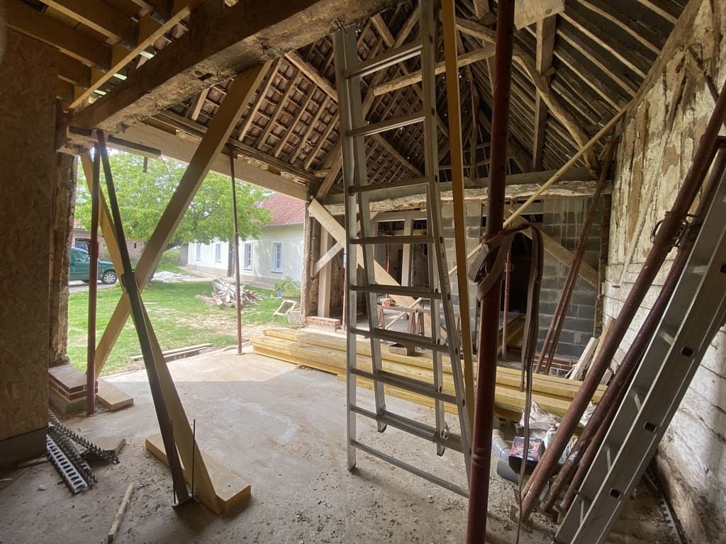 Chantier : Vue intérieure d'un bâtiment en rénovation, montrant les poutres apparentes, les supports et les échafaudages.
