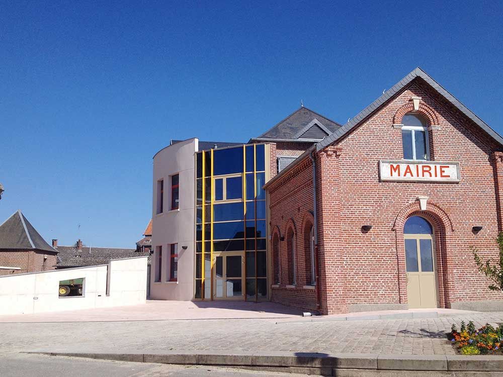 Hôtel de ville en briques et en verre, enseigne « Mairie ». Ciel bleu.