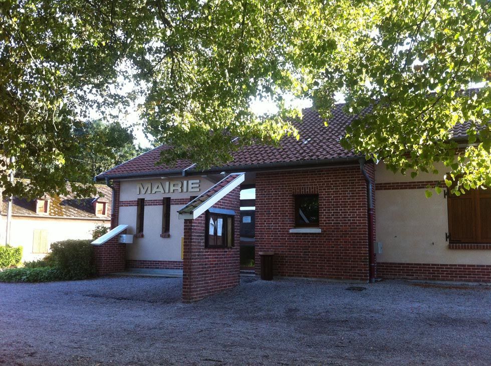 Bâtiment de la mairie en briques rouges avec toit de tuiles, ombragé par des arbres.