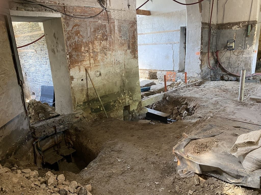 Rénovation intérieure : débris de démolition au sol, ouverture sur une autre pièce, mur apparent.