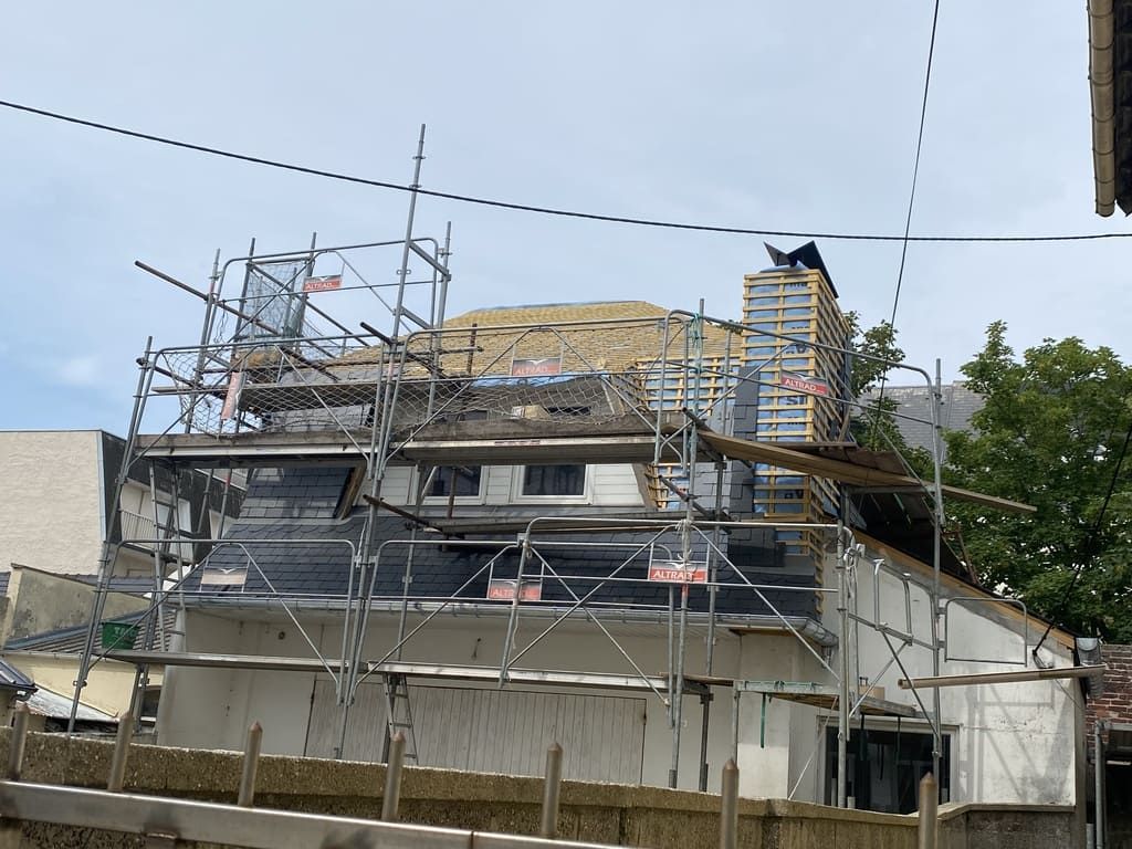 Toiture du bâtiment en construction ; des échafaudages entourent la structure.