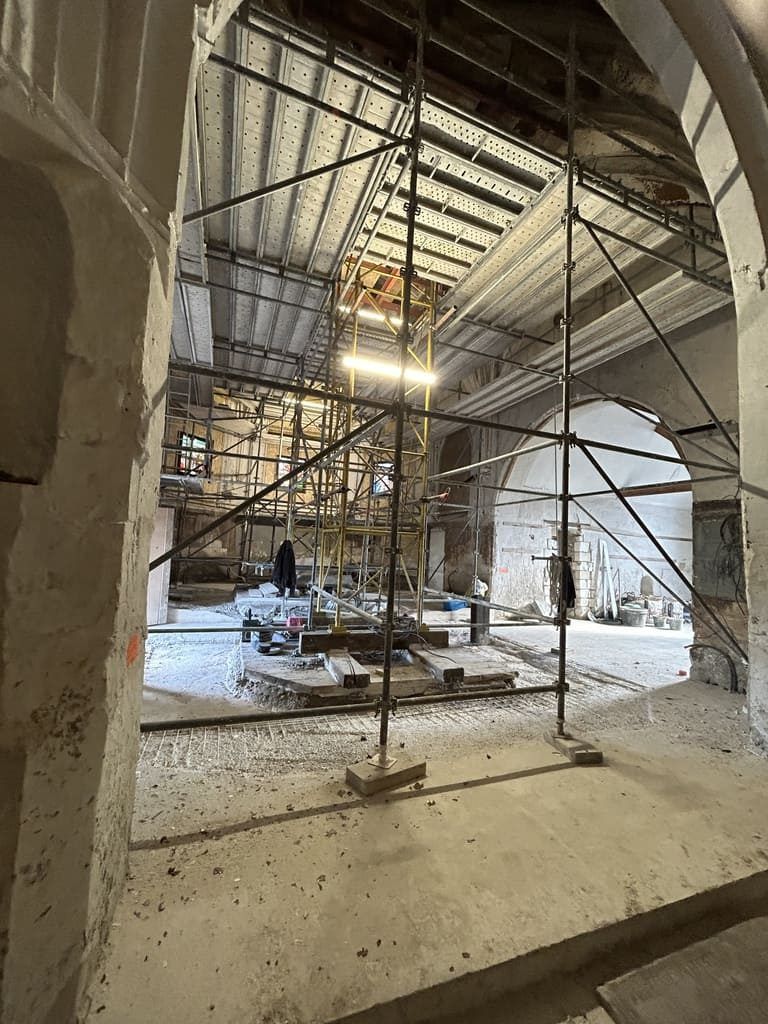 Intérieur d'un bâtiment en rénovation, avec échafaudages et matériaux de construction.