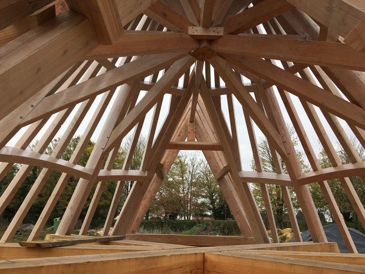 Construction à ossature bois, vue intérieure avec poutres triangulaires et radiales.