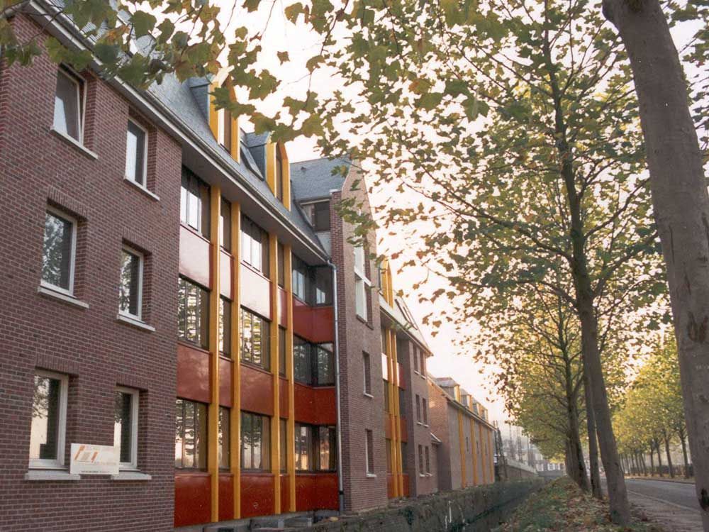 Immeuble d'appartements en briques rouges avec des éléments en bois et des arbres.