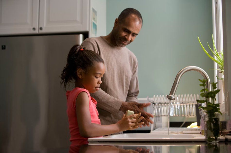 Un père et sa fille se lavant les mains dans l'évier d'une cuisine