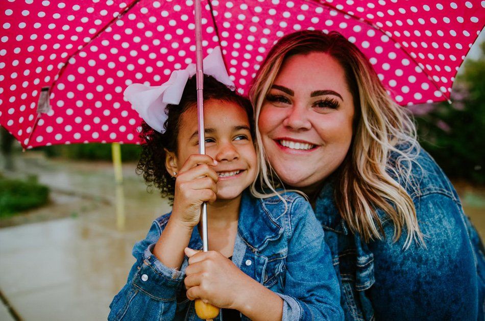 Femme souriante avec sa fille sous un parapluie