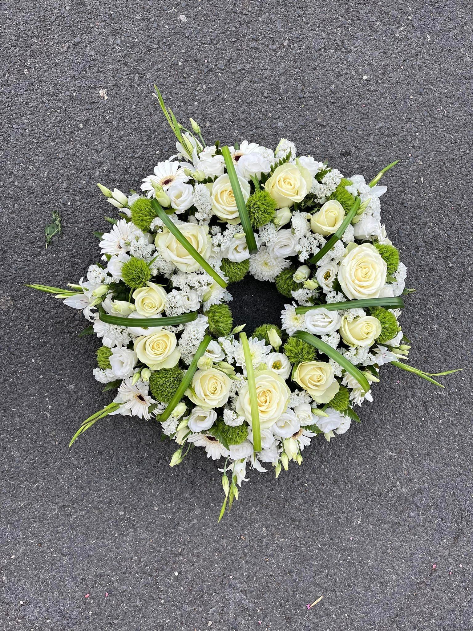 Couronne de fleurs blanches avec des touches de vert sur un trottoir gris
