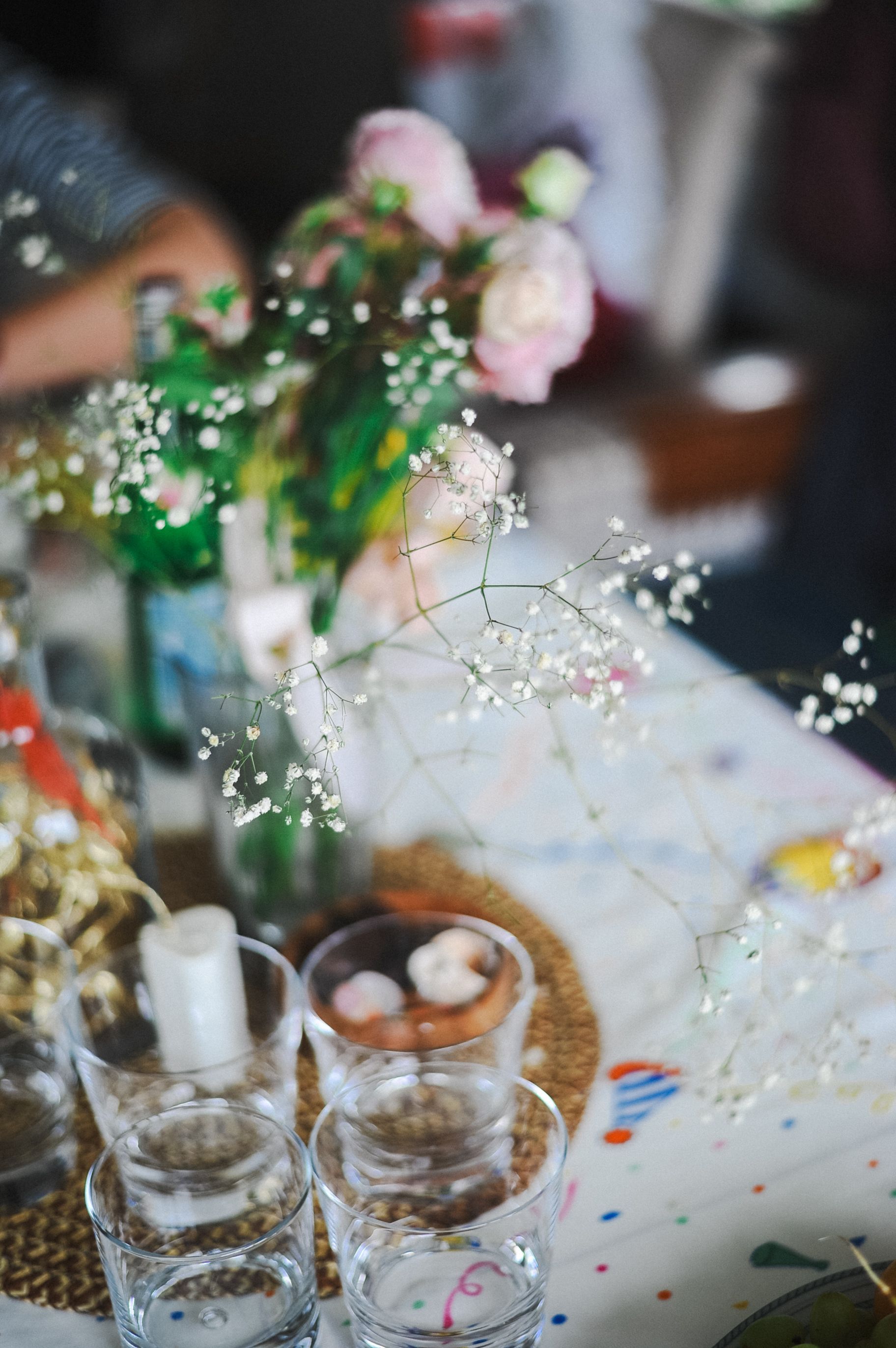 Des bols en verre et des bougies sur une table recouverte de confettis avec un centre de table floral