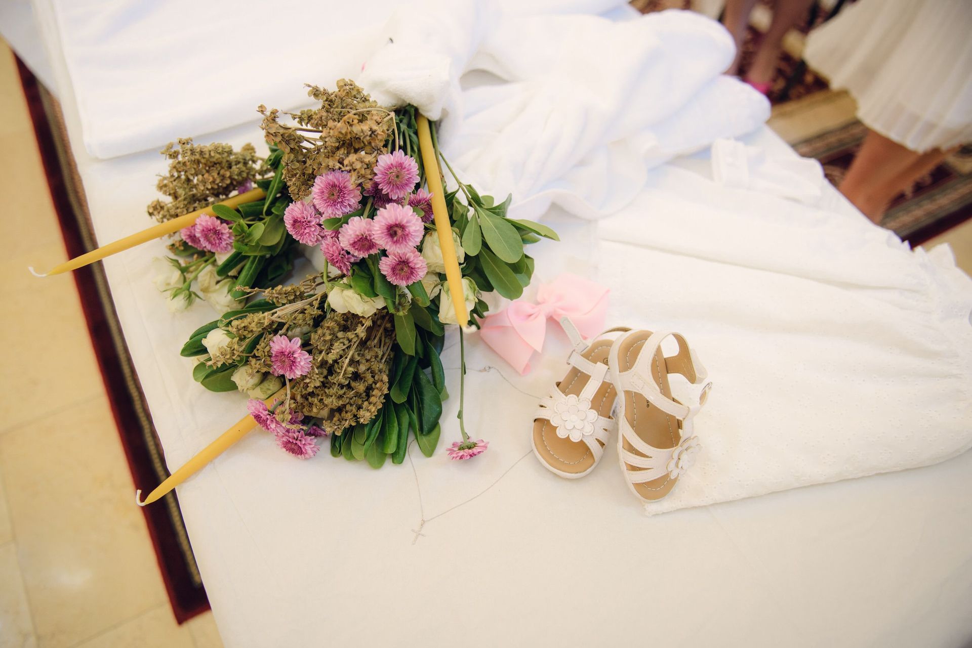 Un bouquet de mariée avec des fleurs roses et une paire de chaussures de mariée blanches sur un lit
