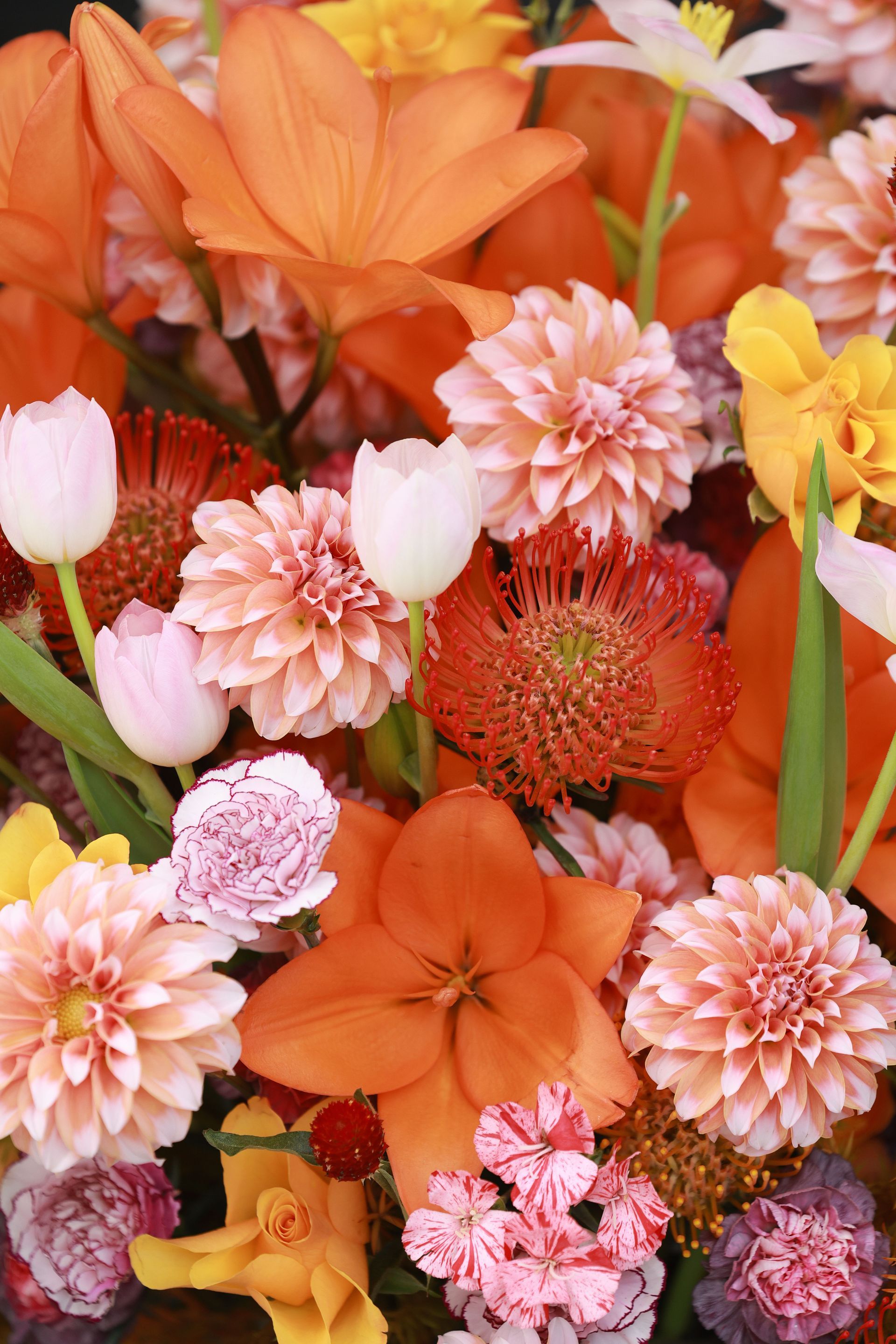 Bouquet dense de fleurs orange, roses et jaunes assorties