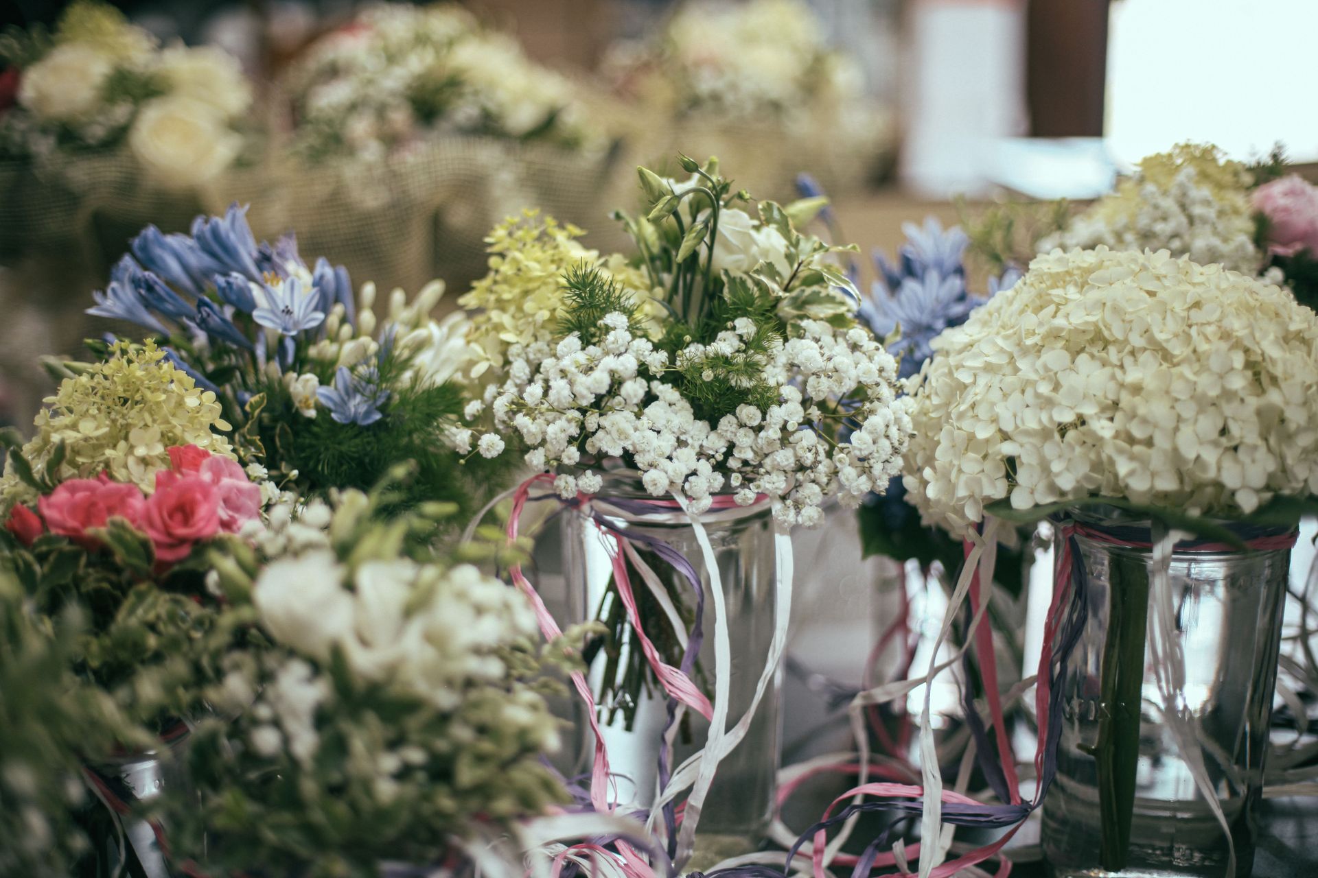 Des bouquets de fleurs assortis dans des vases en verre avec des rubans pastel sur une table