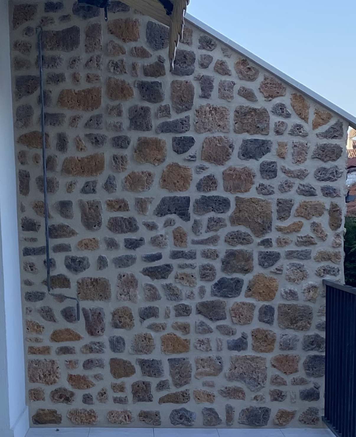 Mur en pierre avec des pierres beiges et grises de différentes tailles.