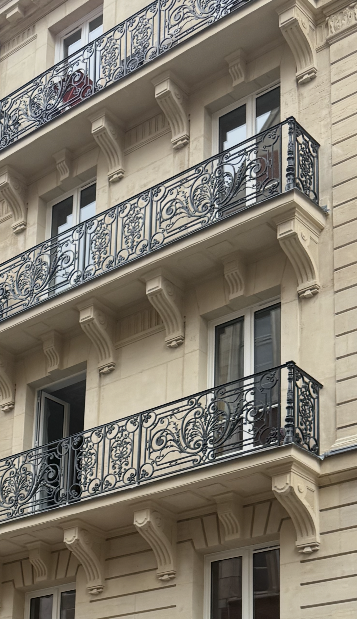 Façade de bâtiment beige avec balcons en fer forgé.