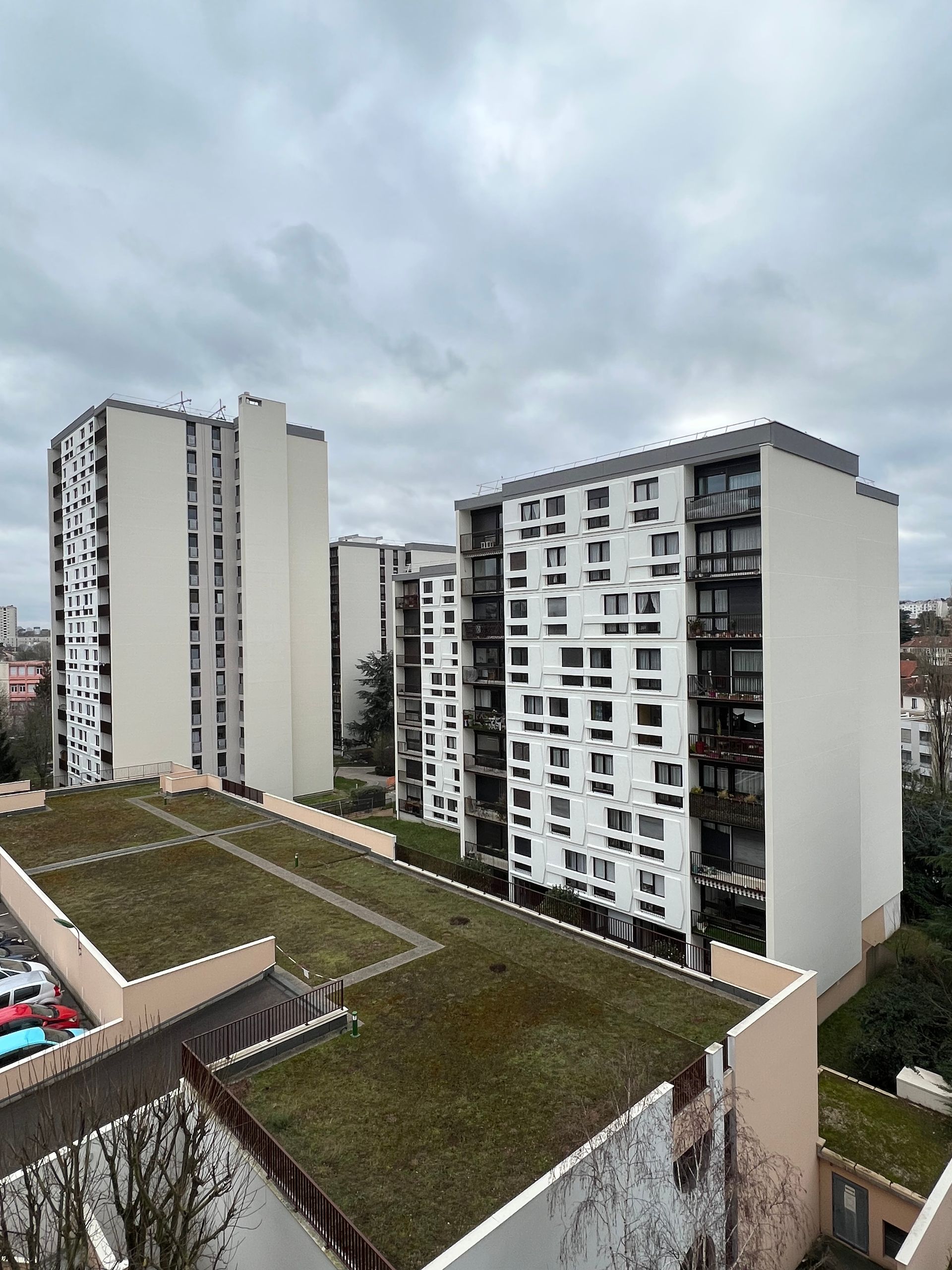 Des bâtiments avec de nombreuses fenêtres et des toits verts plats sous un ciel nuageux.